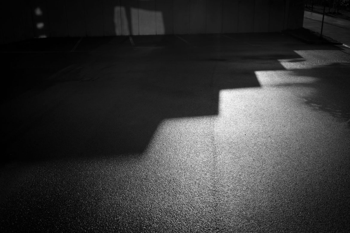 Nasser Asphalt mit Schatten und Sonnenlicht